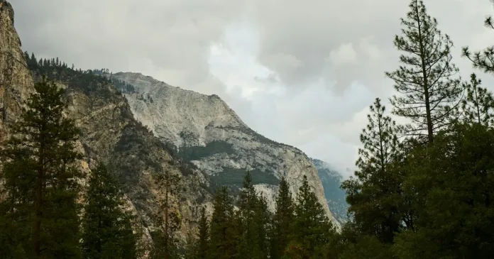 Skupiny návštěvníků na parkovišti u Yellowstonu s foťáky a průvodci, v pozadí kouří gejzír