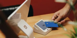 Platba kartou v USA: DCC, bankomaty a hotovost Cestovatel vkládá platební kartu do terminálu na pokladně amerického obchodu