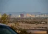 Výlety z Las Vegas: parky, časy i ceny 2026 Pohled z okna jedoucího auta - silnice vedoucí z Las Vegas do pouště s městem viditelným v zpětném zrcátku