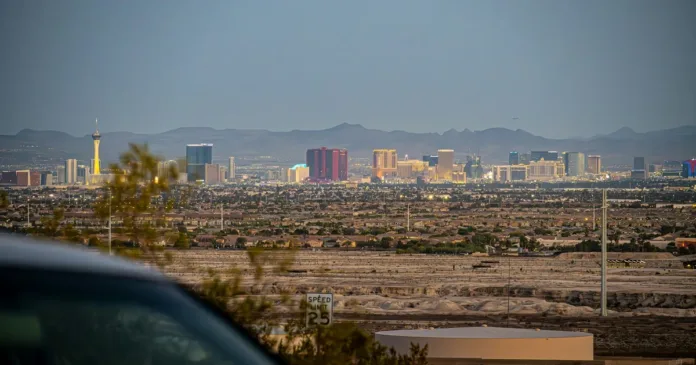 Pohled z okna jedoucího auta - silnice vedoucí z Las Vegas do pouště s městem viditelným v zpětném zrcátku