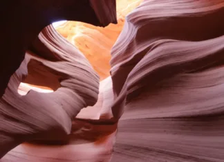 Antelope Canyon a Horseshoe Bend: kompletní průvodce Návštěvníci procházejí úzkým slot canyonem se stěnami vysoko nad hlavami, v poledním slunci